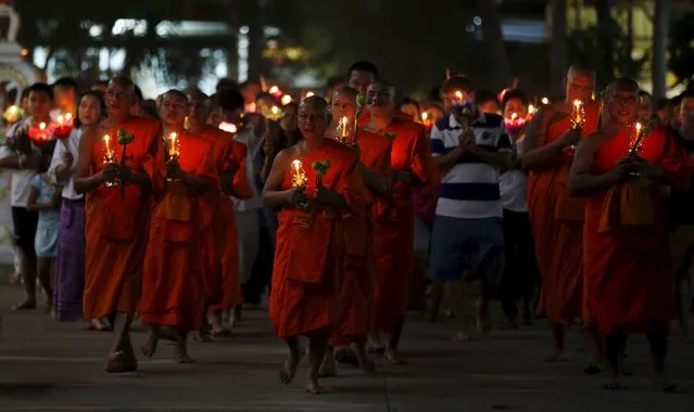 Buddhists carry candles while circling a temple during Makha Bucha Day in Nonthaburi province, on the outskirts of Bangkok, Thailand, February 22, 2016. (Photo by Chaiwat Subprasom/Reuters)