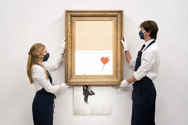 Art handlers at Sotheby's auction house hold Banksy's “Love is in the Bin”, before it returns to auction at Sotheby's, London, Friday, September 3, 2021. A Banksy artwork that was sensationally shredded just after it sold for $1.4 million us up for sale again – at several times the price. Sotheby’s said Friday that “Love is in the Bin” will be offered at an Oct. 14 auction in London, with a pre-sale estimate of 4 million pounds to 6 million pounds ($5.5 million to $8.3 million). (Photo by Dominic Lipinski/PA Wire via AP Photo)