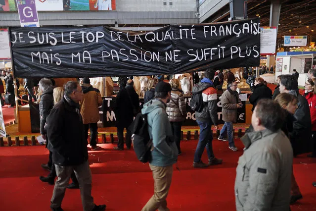 Visitors walk past a banner reading “I am on the top of French quality but my passion is no longer sufficient” displayed at a stand during the International Agricultural Show in Paris, France, February 29, 2016. The Paris Farm Show runs from February 27 to March 6, 2016. (Photo by Benoit Tessier/Reuters)