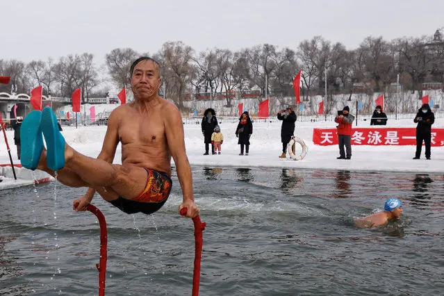 A winter swimmer shows off his skills after diving into a frozen Songhua river, during a winter swimming event at the International Ice and Snow Festival, in Harbin, Heilongjiang province, China on January 6, 2024. (Photo by Tingshu Wang/Reuters)