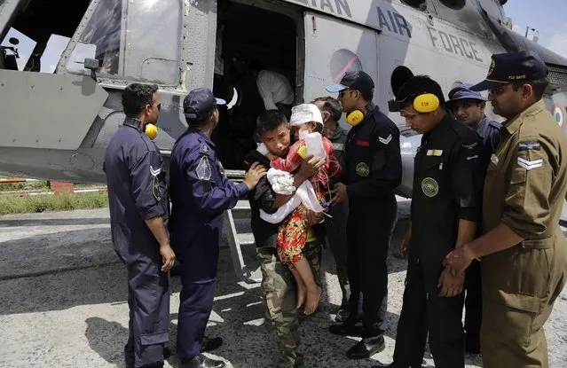A child injured in Saturday's earthquake, is carried by a Nepalese soldier after being evacuated in an Indian Air Force helicopter at the airport in Kathmandu, Nepal, Monday, April 27, 2015. (Photo by Altaf Qadri/AP Photo)