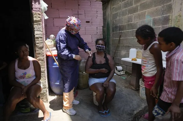 Nurse Rosaura Rodriguez inoculates a woman with a dose of the Sinopharm COVID-19 vaccine during house to house vaccinations in the popular neighborhood of El Valle in Caracas, Venezuela, Monday, September 27, 2021. (Photo by Ariana Cubillos/AP Photo)
