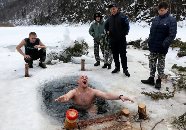 Pupils of a local rehabilitation centre for children watch their teacher Ilya Shelko taking a dip in the cold waters of the ice-covered Mana River in the Siberian Taiga area near Mansky village in Krasnoyarsk Region, Russia on March 24, 2019. (Photo by Ilya Naymushin/Reuters)