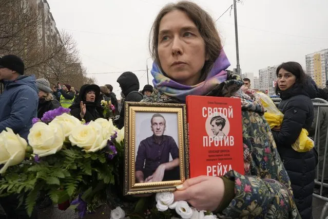 A woman holds a portrait of Alexei Navalny and a book titled “A saint against the Reich” as people gather outside the Church of the Icon of the Mother of God Soothe My Sorrows, in Moscow, Russia, Friday, March 1, 2024. Relatives and supporters of Alexei Navalny are bidding farewell to the opposition leader at a funeral in southeastern Moscow, following a battle with authorities over the release of his body after his still-unexplained death in an Arctic penal colony. (Photo by AP Photo)