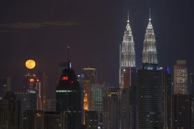 The mid-autumn full moon is seen above the city of Kuala Lumpur during the Mid-Autumn Festival, Tuesday, September 21, 2021. The festival falls on the 15th day of the 8th lunar month of the Chinese calendar and is marked by Chinese families and friends gathering to eat Chinese moon cakes and pomelos together. (Photo by Vincent Thian/AP Photo)