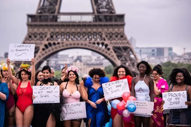 Models pose with placards in front of the Eiffel Tower during The All Sizes Catwalk event in Paris on April 28, 2019. About 40 women of different body shapes gathered for the event on April 28 at Trocadero to promote self-acceptance. (Photo by Martin Bureau/AFP Photo)