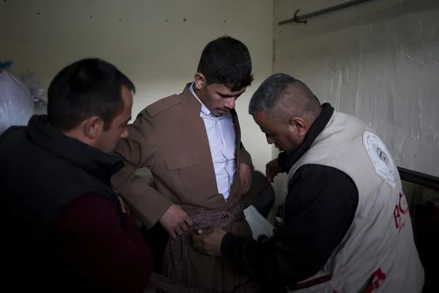 Hussein Zeino Danoon, 25, gets dressed in Kurdish traditional clothing for his wedding on Thursday, February 16, 2017. He married 15-year-old Shahad Ahmed Abed in the Khazer camp for displaced people from Mosul. (Photo by Bram Janssen/AP Photo)