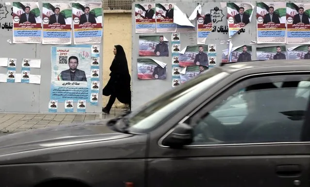 A veiled woman walks next to the electoral posters of candidates running in the upcoming parliamentary elections, along a street in Tehran, Iran, 26 February 2024. Iranians on 01 March 2024 will vote for new members of Iran's parliament, and for the Assembly of Experts, the body in charge of appointing Iran's Supreme Leader. (Photo by Abedin Taherkenareh/EPA/EFE)