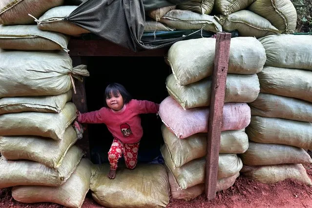 This photo taken on December 14, 2023 shows a girl playing in a bomb shelter near her home amid clashes between the ethnic minority armed group Ta'ang National Liberation Army (TNLA) and Myanmar's military in Namhsan Township in Myanmar's northern Shan State. (Photo by AFP Photo/Stringer)