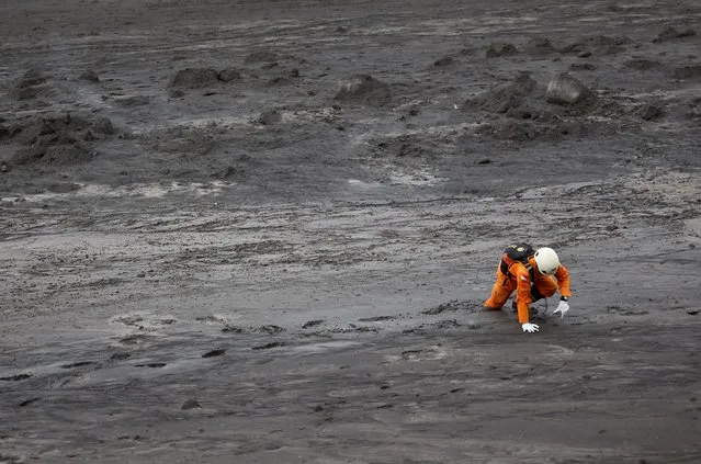 A rescue worker is stuck in mud in the aftermath of the eruption of Mount Semeru volcano, in  Curah Kobokan, Indonesia, December 7, 2021. (Photo by Willy Kurniawan/Reuters)