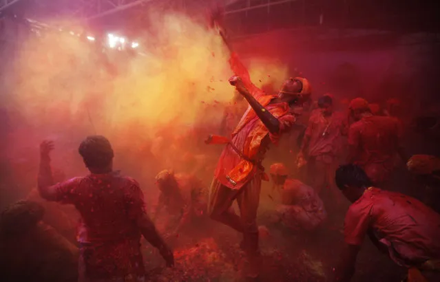 Hindu men from the village of Nangaon throw colored powder on others as they play holi at the Ladali or Radha temple before the procession for the Lathmar Holi festival, the legendary hometown of Radha, consort of Hindu God Krishna, in Barsana 115 kilometers ( 71 miles) from New Delhi, India, Sunday, March 9, 2014. (Photo by Altaf Qadri/AP Photo)