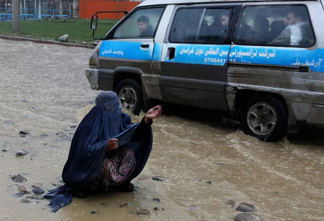 An Afghan woman begs on a flooded street in the city of Kabul, Afghanistan, Sunday, March 16, 2014. (Photo by Rahmat Gul/AP Photo)