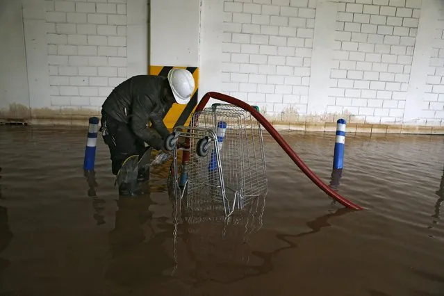 A man works in a flooded commercial center access in Santiago, April 17, 2016. (Photo by Ivan Alvarado/Reuters)