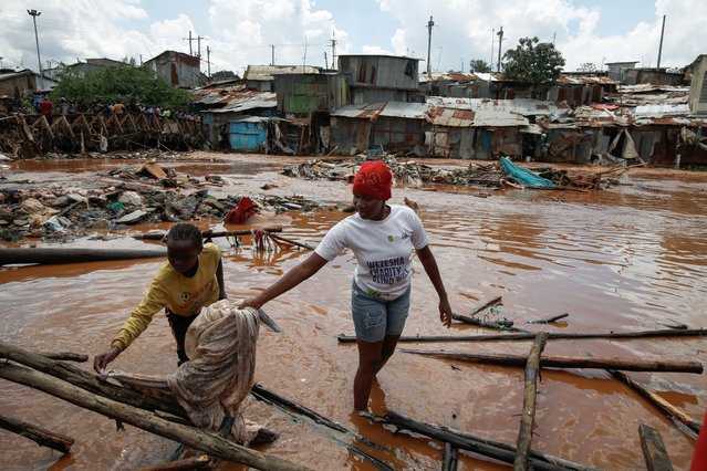 Residents wade through flood waters after the Nairobi river burst its banks and destroyed their homes within the Mathare valley settlement in Nairobi, Kenya on April 24, 2024. (Photo by Monicah Mwangi/Reuters)