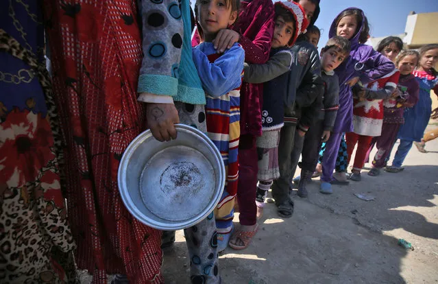 Displaced Iraqi children stand in queue to receive food rations in Mosul's western Tal al-Rumman neighbourhood on March 10, 2017, during an offensive to retake the western parts of the city from the jihadists. (Photo by Ahmad Al-Rubaye/AFP Photo)