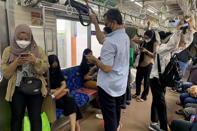 People wear face masks as a precaution against the coronavirus inside a train in Jakarta, Indonesia, Tuesday, December 28, 2021. (Photo by Tatan Syuflana/AP Photo)