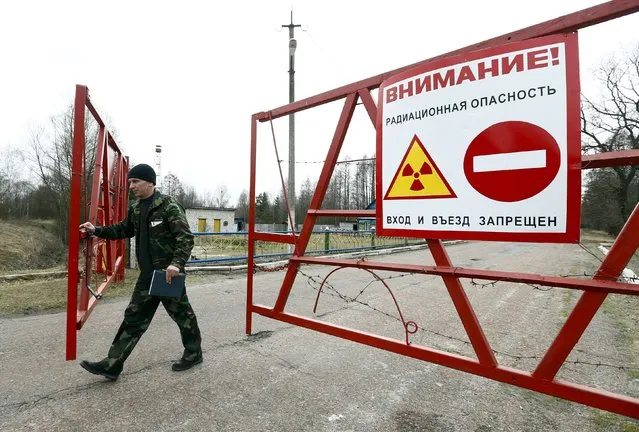 An employee opens the gate at the checkpoint “Maidan” in the 30 km (19 miles) exclusion zone around the Chernobyl nuclear reactor near the abandoned village of Babchin, Belarus, March 11, 2016. (Photo by Vasily Fedosenko/Reuters)