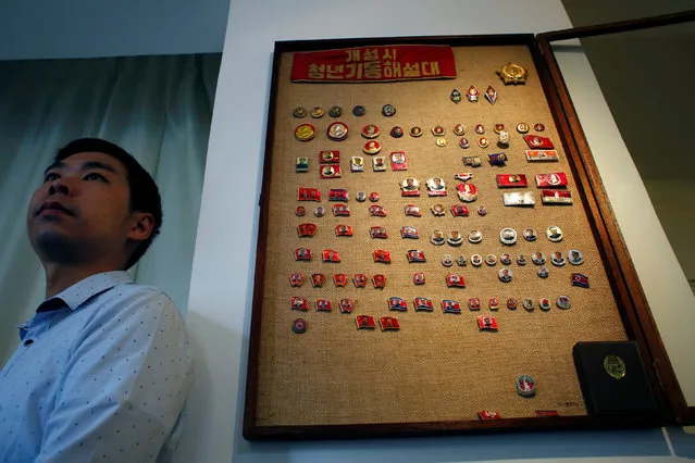 Thomas Hui poses with his glass case displaying more than 100 pins featuring former North Korean leaders Kim Il Sung and Kim Jong Il at his apartment in Hong Kong, China April 11, 2016. Collector Thomas Hui, a former bank employee in Hong Kong, who is fascinated by North Korean pins and badges, has gathered over 100 featuring former leaders Kim Il Sung and Kim Jong Il, and has been buying and trading these Communist accessories since 2008. (Photo by Bobby Yip/Reuters)
