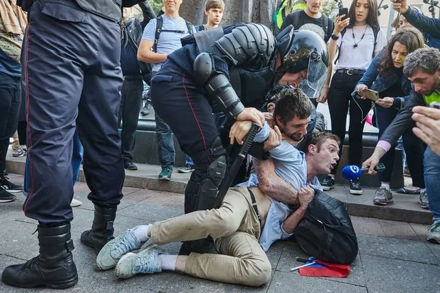 Timur Olevskiy, a TV anchor for Current Time TV, conducts an interview with a man as he is being detained by police at a rally to demand free municipal elections in Moscow, Russia on August 3, 2019. (​Photo by Andrei Zolotov/MBKh Media)