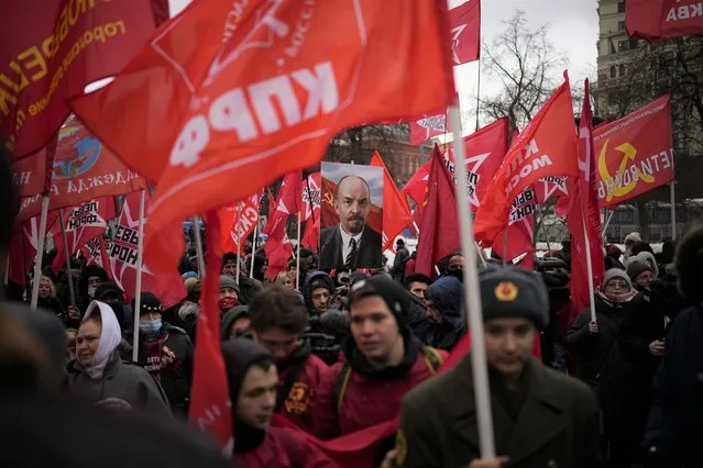 Communists' party supporters with red flags and a portrait of Soviet Founder Vladimir Lenin, center, attend the national celebrations of the 'Defender of the Fatherland Day' near the Kremlin in the Revolution Square in Moscow, Russia, Wednesday, February 23, 2022. The Defenders of the Fatherland Day, celebrated in Russia on February 23, honors the nation's military and is a nationwide holiday. (Photo by Alexander Zemlianichenko/AP Photo)