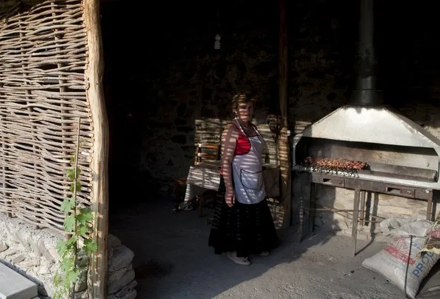 A woman fries meat on a wood-fired grill at a cafe in Leningori (or Akhalgori), in the breakaway region of South Ossetia, Georgia, July 6, 2015. (Photo by Kazbek Basaev/Reuters)