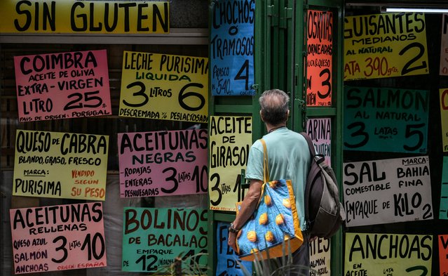 A man observes food prices displayed at the facade of a supermarket in Caracas on May 8, 2024. (Photo by Juan Barreto/AFP Photo)