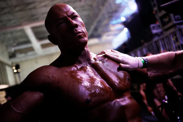 A competitor is smeared with oil as he warms up backstage during the Arnold Classic South America bodybuilding event in Sao Paulo, Brazil, April 22, 2017. (Photo by Nacho Doce/Reuters)