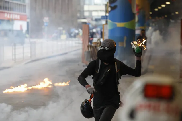 A protestor prepares to throw molotov cocktail in Hong Kong, Sunday, September 29, 2019. Riot police fired tear gas Sunday after a large crowd of protesters at a Hong Kong shopping district ignored warnings to disperse in a second straight day of clashes, sparking fears of more violence ahead of China's National Day. (Photo by Vincent Thian/AP Photo)