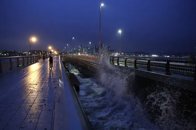 A man walks along the bridge connecting to Enoshima Island in Fujisawa, west of Tokyo, Friday, October 11, 2019. A powerful typhoon was forecast to bring 2 feet of rain and damaging winds to the Tokyo area this weekend, and Japan's government warned people Friday to stockpile supplies and evacuate before it's too dangerous. (Photo by Jae C. Hong/AP Photo)