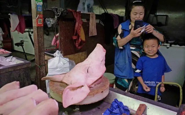 A Chinese vendor waits for customers beside a pig's head on her pork stall at a wholesale market in Beijing, China, 23 August 2019. Reports state that the Chinese government has decided to step up efforts to stabilize pork production and ensure the pork supply following the effects of African swine fever on the industry. (Photo by Wu Hong/EPA/EFE/Rex Features/Shutterstock)