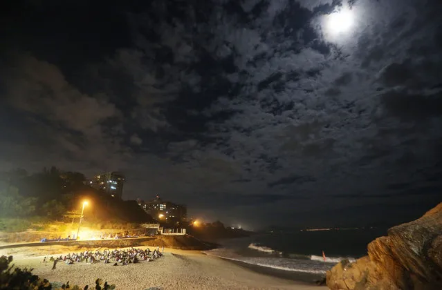 People gather beneath the full moon during a full moon meditation session on Praia do Diabo beach on May 21, 2016 in Rio de Janeiro, Brazil. The city is set to host the Rio 2016 Olympic Games in August. (Photo by Mario Tama/Getty Images)