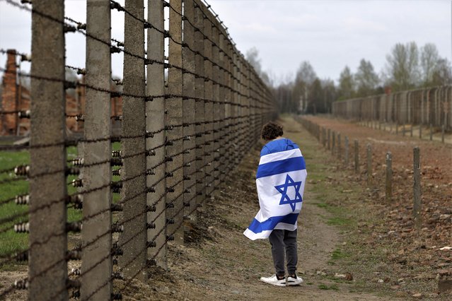 A man with an Israeli flag participates in the annual “March of the Living'” a trek between two former Nazi-run death camps, in Oswiecim, Poland, Tuesday, April 18, 2023 to mourn victims of the Holocaust and celebrate the existence of the Jewish state. (Photo by Michal Dyjuk/AP Photo)