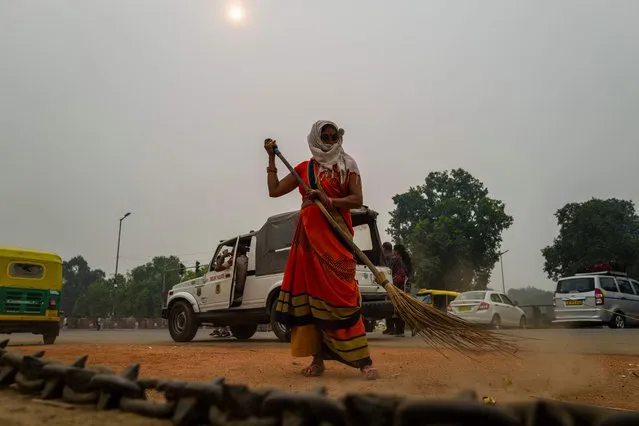 A woman sweeps a street near India Gate under heavy smog in New Delhi on October 29, 2019. Photo by Jewel Samad/AFP Photo)