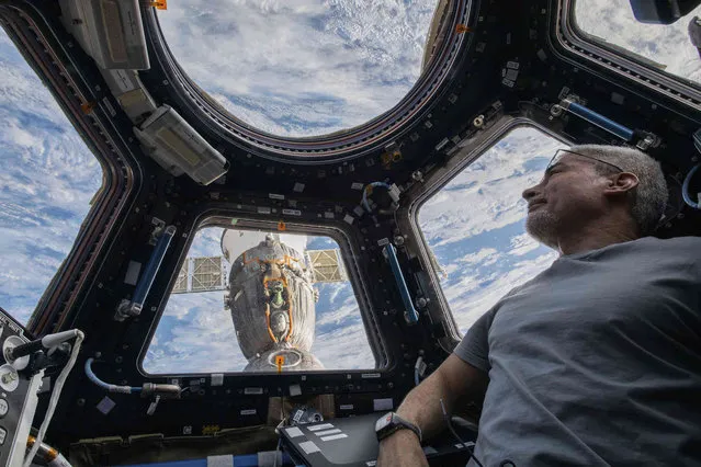 In this photo provided by NASA, U.S. astronaut and Expedition 66 Flight Engineer Mark Vande Hei peers at the Earth below from inside the seven-windowed cupola, the International Space Station's window to the world on Feb. 4, 2022. The Soyuz MS-19 crew ship is docked to the Rassvet module in the background. Vande Hei has made it through nearly a year in space, but in March 2022 faces what could be his trickiest assignment yet: riding a Russian capsule back to Earth in the midst of deepening tensions between the countries. (Photo by Kayla Barron/NASA via AP Photo)