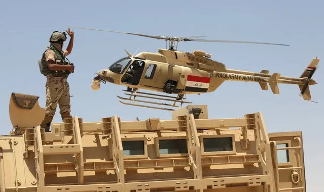 An Iraqi helicopter flies over a soldier in Husaybah, in Anbar province July 22, 2015. Iraqi security forces and Sunni tribal fighters launched an offensive on Tuesday to dislodge Islamic State militants and secure a supply route in Anbar province, police and tribal sources said. (Photo by Reuters/Stringer)
