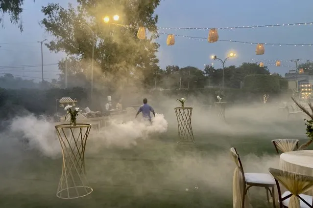 A man fumigates to drive away mosquitoes at a lawn where a wedding reception is scheduled in New Delhi, India, Wednesday, April 13, 2022. (Photo by Ashwini Bhatia/AP Photo)