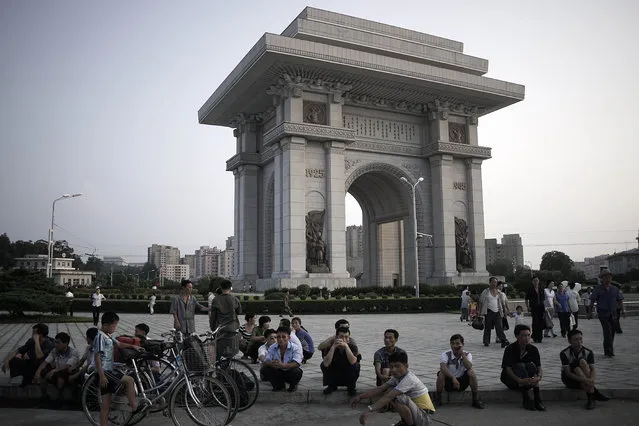 North Koreans sit in front of a structure known as the Arch of Triumph in the background, as they watch students participate in a mass dance, Monday, July 27, 2015, in Pyongyang, North Korea as part of celebrations for the 62nd anniversary of the armistice that ended the Korean War. (Photo by Wong Maye-E/AP Photo)