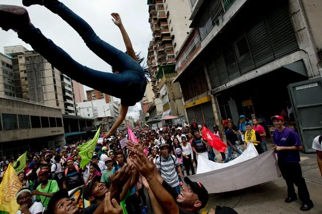 Supporters of Venezuela's President Nicolas Maduro toss a fellow supporter into the air during a rally in Caracas, Venezuela, Wednesday, June 1, 2016. Government supporters and state employees held a rally against “foreign intervention” in Venezuela's affairs. (Photo by Fernando Llano/AP Photo)