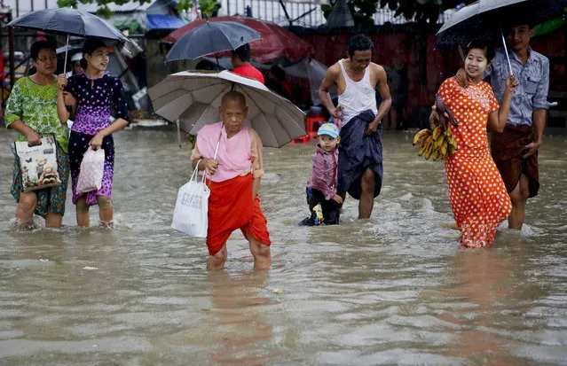 People walk through a flooded road at downtown area of Yangon, Myanmar, 31 July 2015. Heavy monsoon rains caused floods around Myanmar with dozens deaths being reported as thousands are fleeing their homes in several states and divisions across the country. In Myanmar monsoon starts at the beginning of June and ends in September. (Photo by Lynn Bo Bo/EPA)