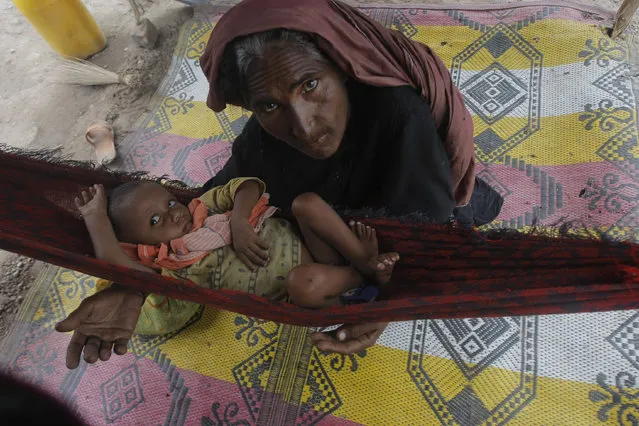 A woman sits with her son after being displaced due to heavy rains in a suburb of Peshawar, Pakistan, Thursday, July 23, 2015. (Photo by Mohammad Sajjad/AP Photo)