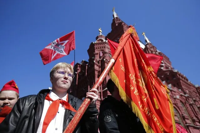 A boy in red neckerchief holds a red flag standing on Red Square during a ceremony to celebrate joining the Pioneers organization and 100th anniversary of the All-Union Pioneer Organization, in Moscow, Russia, Sunday, May 22, 2022. Pro-Communist Russians are trying to preserve the Young Pioneers, which used to be the Communist league for pre-teens in the Soviet Union. (Photo by AP Photo/Stringer)