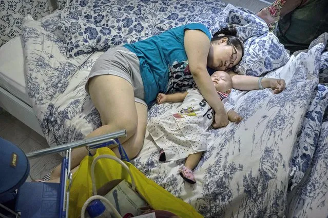 A Chinese shopper sleeps with her child on a bed in the showroom of the IKEA store on July 6, 2014 in Beijing, China. Of the world's ten biggest Ikea stores, 8 of them are in China to cater to the country's growing middle class. The stores are designed with extra room displays given the tendency for customers to make a visit an all-day affair. Store management does not discourage shoppers from sleeping on Ikea furniture, even marking them with signs inviting customers to try them out. (Photo by Kevin Frayer/Getty Images)
