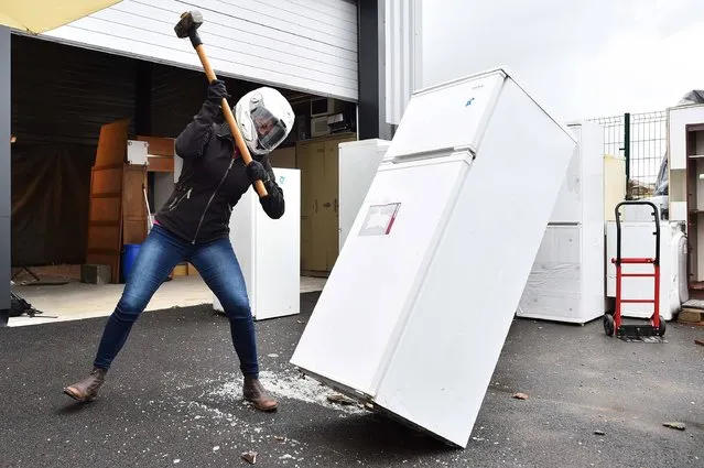 A person destroys a refridgerator with a sledgehammer on June 30, 2017, in Noyal-Chatillon-sur-Seiches, western France. Spraying plates, smashing a fridge or taking a baseball bat to a microwave or golf club, and feel more zen, is a move of a sophrologist who organizes workshops to alleviate stress. (Photo by Jean-Francois Monier/AFP Photo)