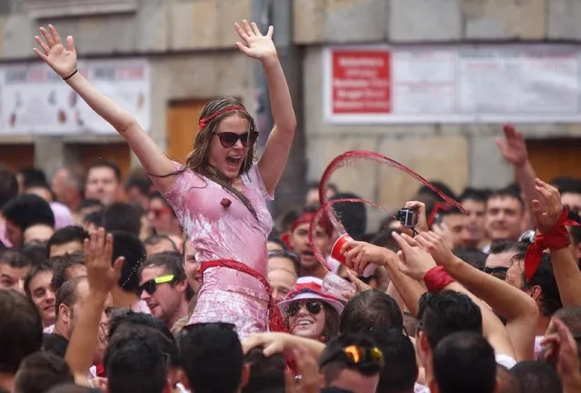 Revellers cheer and throw red wine during the opening and the firing of the “Chupinazo” rocket which starts the 2014 Festival of the San Fermin Running of the Bulls on July 6, 2014 in Pamplona, Spain. The annual Fiesta de San Fermin, made famous by the 1926 novel of US writer Ernest Hemmingway entitled “The Sun Also Rises”, involves the daily running of the bulls through the historic heart of Pamplona to the bull ring. (Photo by Pablo Blazquez Dominguez/Getty Images)