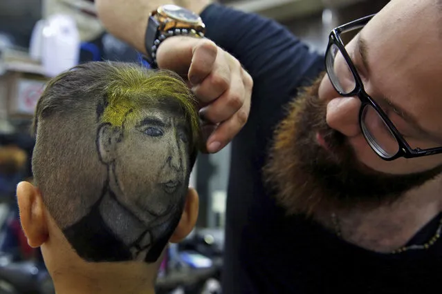 In this Friday, July 14, 2017 photo, Muhannad Khaled Omar, right, prepares an image of U.S. President Donald Trump on the back of a customer's head at his barber shop in Burj al-Barajneh, southern Beirut, Lebanon. In a city full of hair stylists, Omar stands out. He is a 26 year-old Palestinian-Syrian hair stylist known for shaving celebrity portraits into clients’ hair. (Photo by Bilal Hussein/AP Photo)