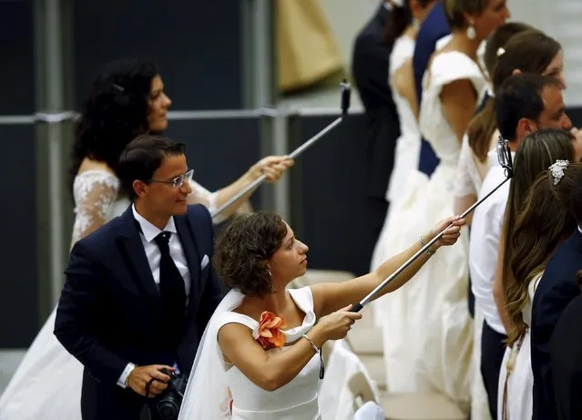 Newly married couples use a “selfie stick” during Pope Francis' Wednesday general audience in Paul VI hall at the Vatican August 12, 2015. (Photo by Remo Casilli/Reuters)