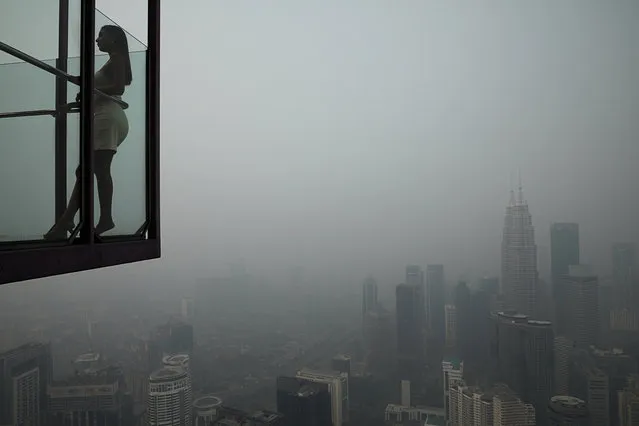 A tourist poses for a picture at Kuala Lumpur Tower with the city skyline in the background shrouded by haze, in Kuala Lumpur, Malaysia, September 13, 2019. (Photo by Lim Huey Teng/Reuters)