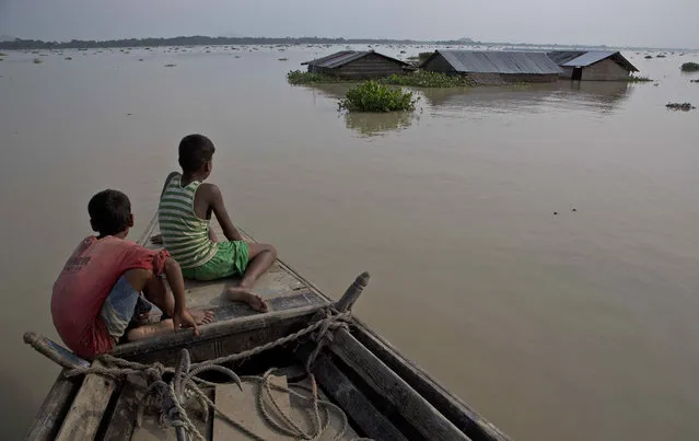 Flood affected villagers travel by boat in floodwaters in Morigaon district, east of Gauhati, northeastern state of Assam, Tuesday, August 15, 2017. Heavy monsoon rains have unleashed landslides and floods that killed dozens of people in recent days and displaced millions more across northern India, southern Nepal and Bangladesh. (Photo by Anupam Nath/AP Photo)