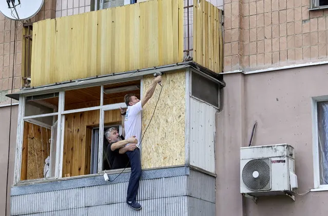 Two men conduct repair works in a flat of a residential building after a missile strike hit the Piatykhatky neighborhood of Kharkiv, northeastern Ukraine, 18 July 2022. According to the head of the Kharkiv regional state administration Oleg Synegubov, military strikes hit a Kharkiv district at night damaging only civil infrastructure with no casualties. Russian troops on 24 February entered Ukrainian territory, starting a conflict that has provoked destruction and a humanitarian crisis. (Photo by Sergey Kozlov/EPA/EFE)