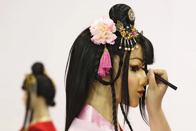 An exhibitor applies eyes make-up to a human-like robot on display at the World Robot Conference at the Yichuang International Conference and Exhibition Centre in Beijing, Wednesday, August 23, 2017. (Photo by Andy Wong/AP Photo)